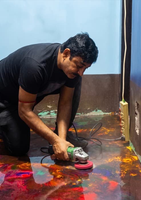 Craftsman polishing a cured multi-coloured epoxy floor with a hand polisher